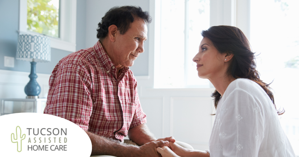 A daughter who is caregiving for her dad who has Alzheimer's disease, lovingly holds his hands.