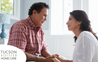 A daughter who is caregiving for her dad who has Alzheimer's disease, lovingly holds his hands.