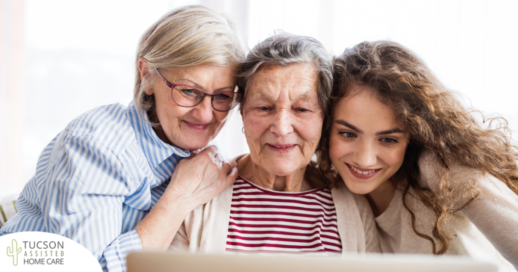 Three generation embrace and look at a computer, representing the sandwich generation.