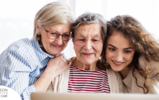 Three generation embrace and look at a computer, representing the sandwich generation.